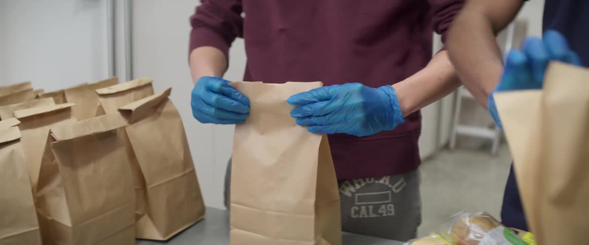 Two teenage boys pack food in to brown paper bags