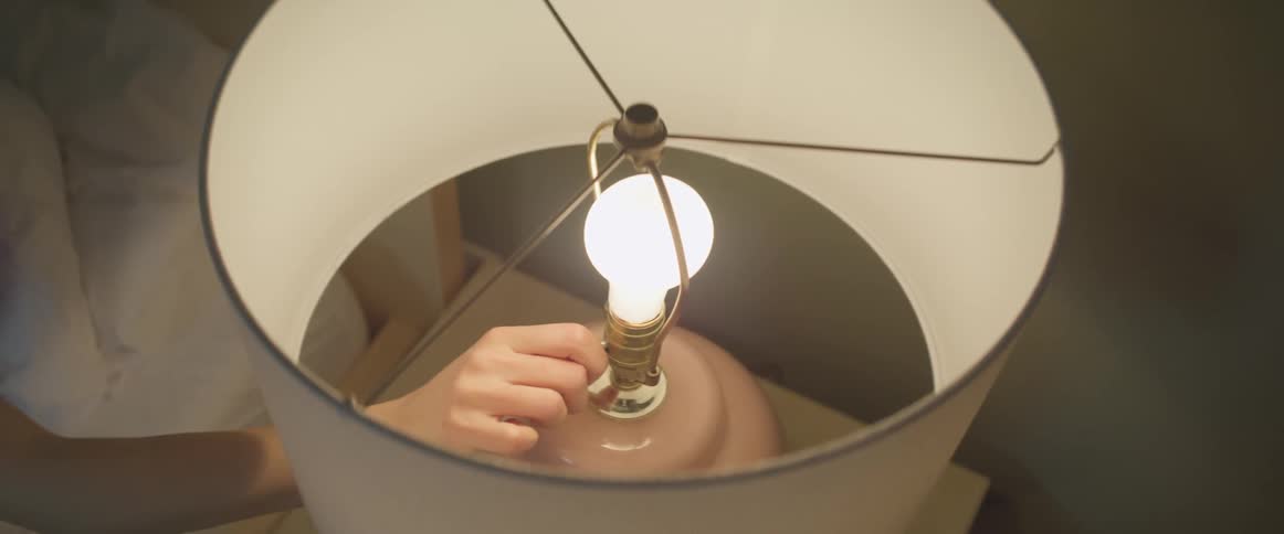 Hand reaches out and turns off bedside lamp