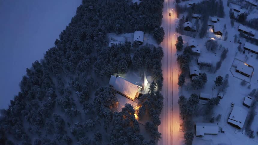 Vehicles drive down a snow covered road past a neighborhood