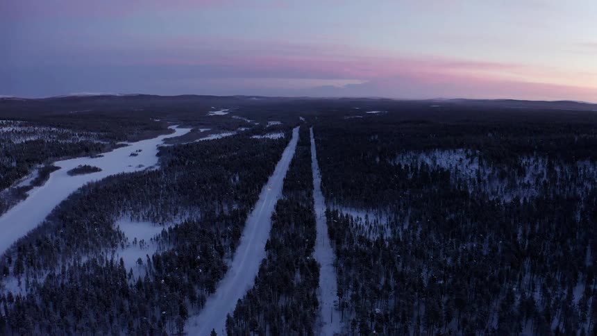 An aerial view of a forest in winter as the evening approaches