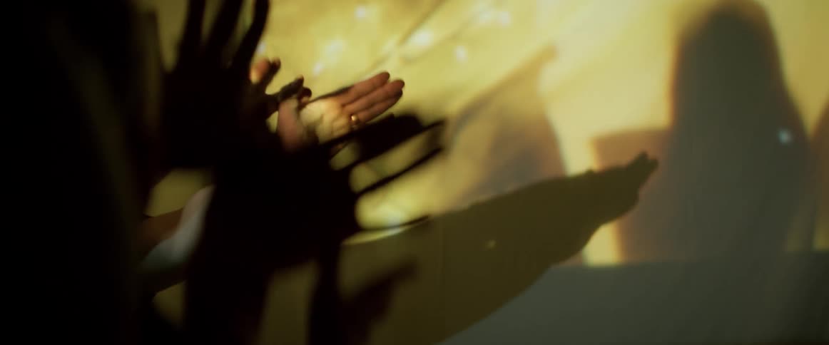 Father and son play making animal hand shadows using a movie projector at home
