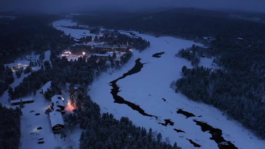 An aerial view of a town in winter as fog approaches at dusk
