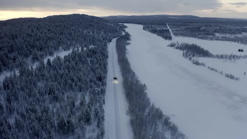 A vehicle drives down a snow covered rural road