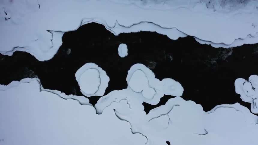 Top down aerial view of a freezing cold river at winter