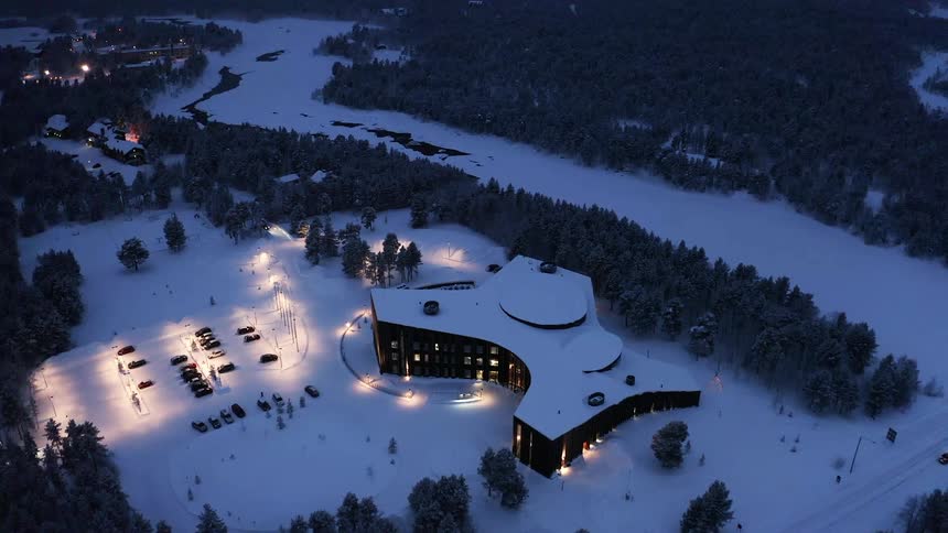 Cars fill up the parking lot of a hotel as snow blankets the countryside