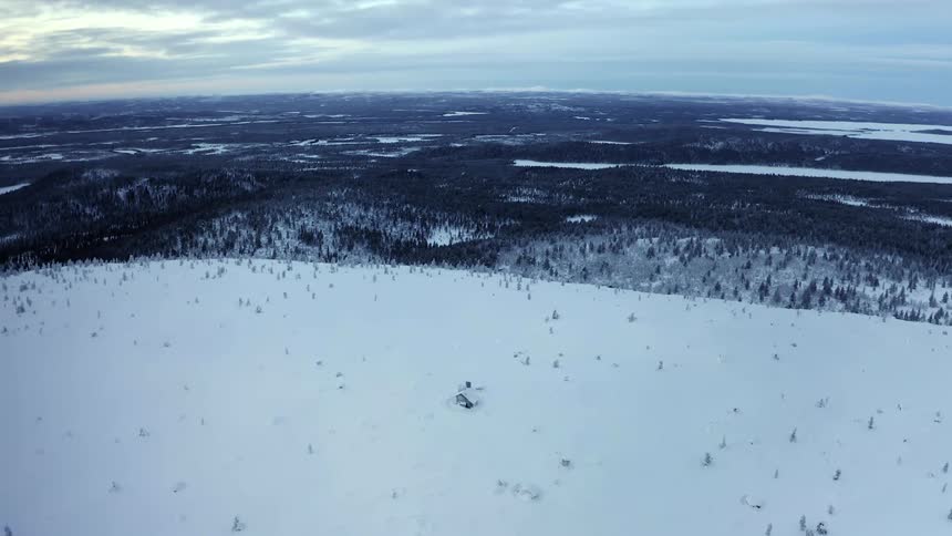 A snow covered ridge overlooks a dense forest in a vast winter wilderness
