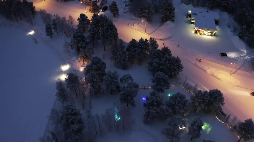 An aerial view of a town in winter with colored lights reflecting on the snow