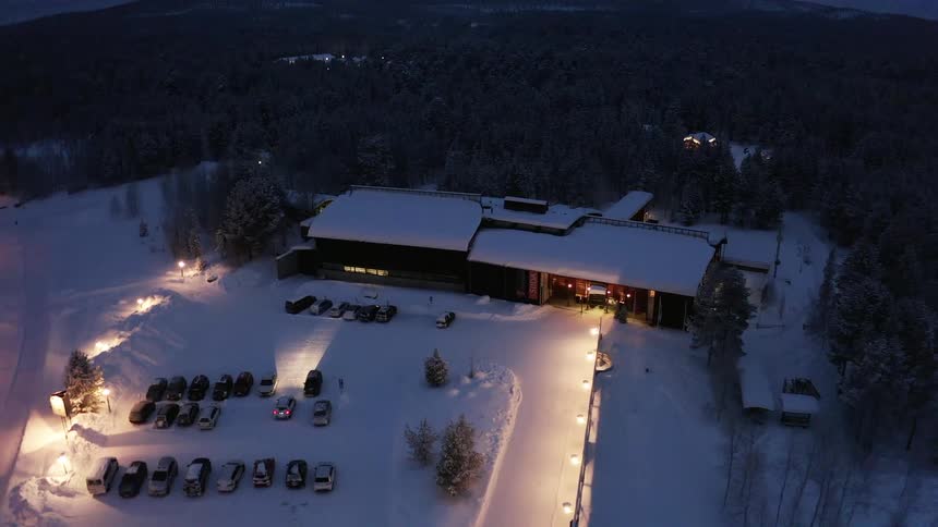 Aerial view of cars parked outside a restaurant at night in the snow