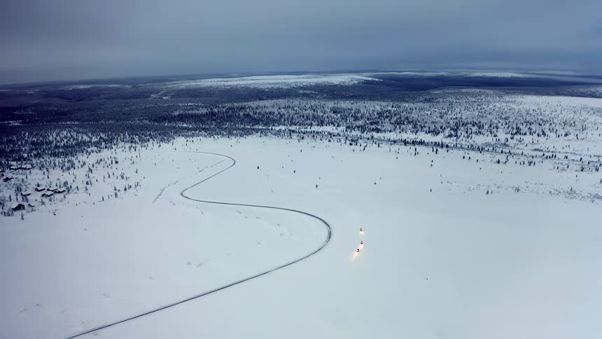 Three snowmobiles with headlights on drive on the snow covered plains at winter
