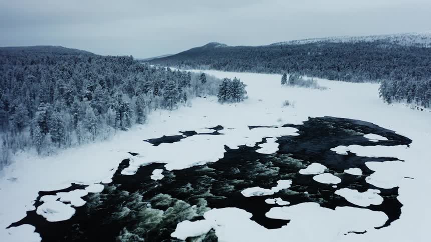 Ice breaking on the surface of a frozen river near pine tree forests at winter