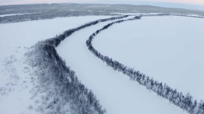 Trees line a frozen river near a forest