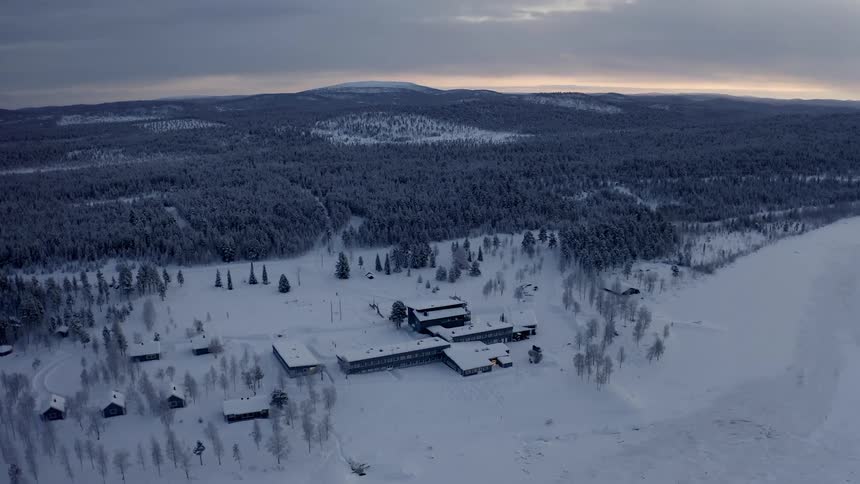 Buildings sit on the snow covered land near the forest