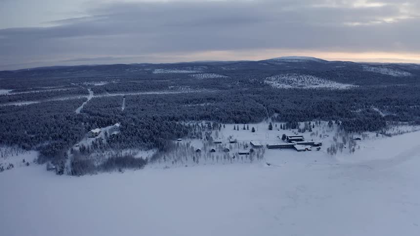 Aerial view of a building in a snowy rural area next to a forest