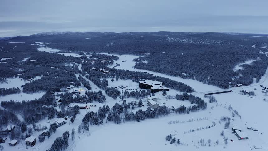 Snow covers town occupying forest and plains with mountains on horizon