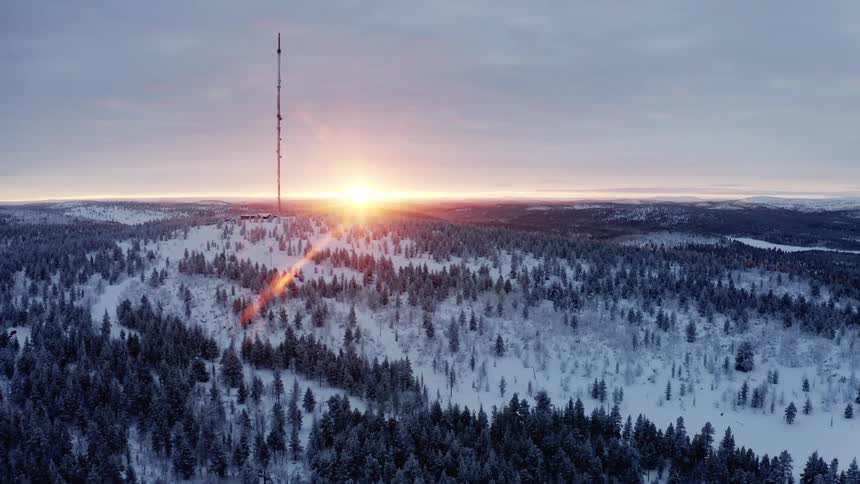 Communications antenna in the snow covered hills at sunset