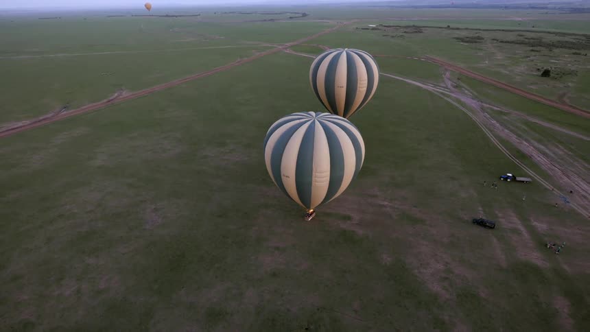 Aerial view of two hot air balloons traveling over a field