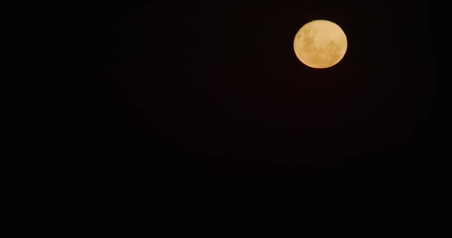 A flashing light in the dark with a full moon up above