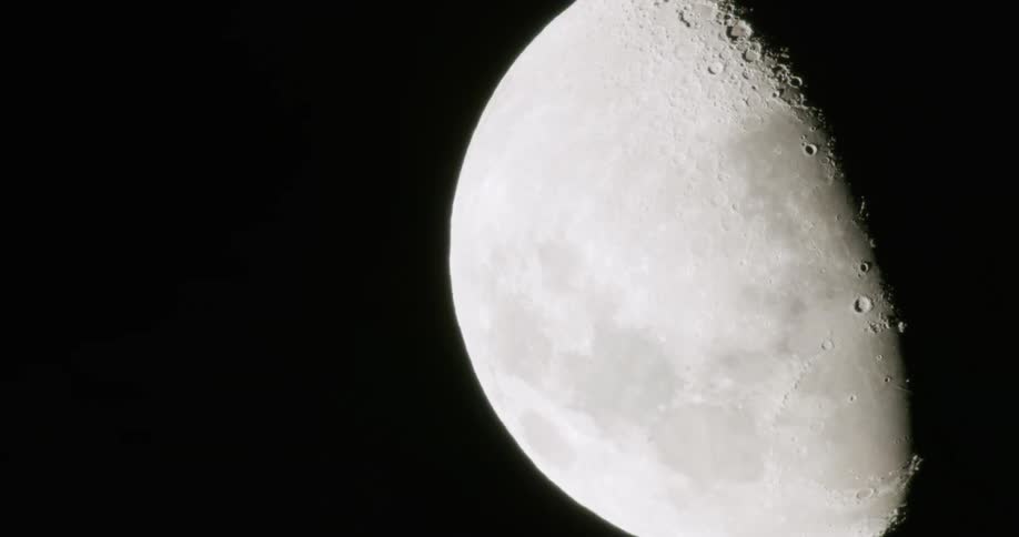 A half moon shines in the night sky