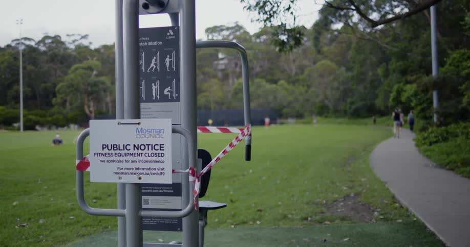 People walking in a park with a notice that the fitness equipment is all closed