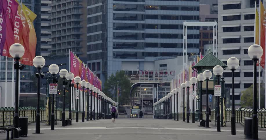 A person walks a large sidewalk towards a large city building