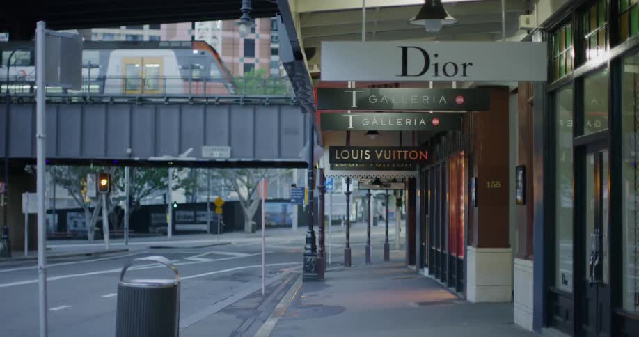 A train moves over a street near some stores in a downtown area