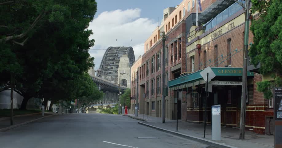 Empty street leads past hotel toward arched bridge