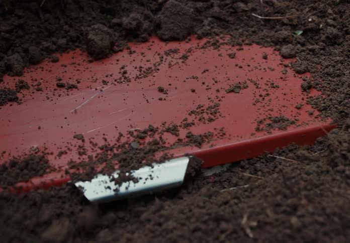 A person is digging up a box in the dirt