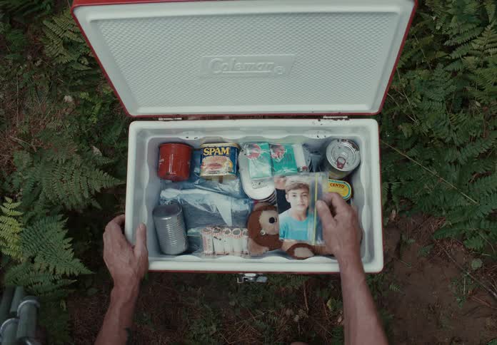 A man taking a photograph in a plastic bag from a portable cooler