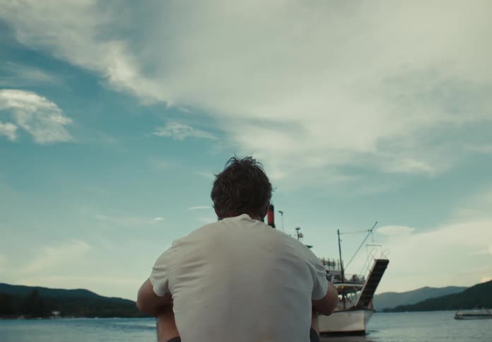 A man sitting on the shore watching boats