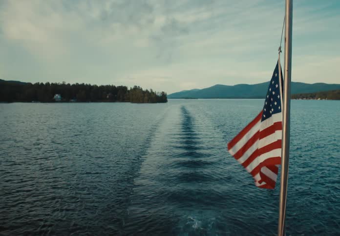 A flag on the back of a boat and a view of the water behind it