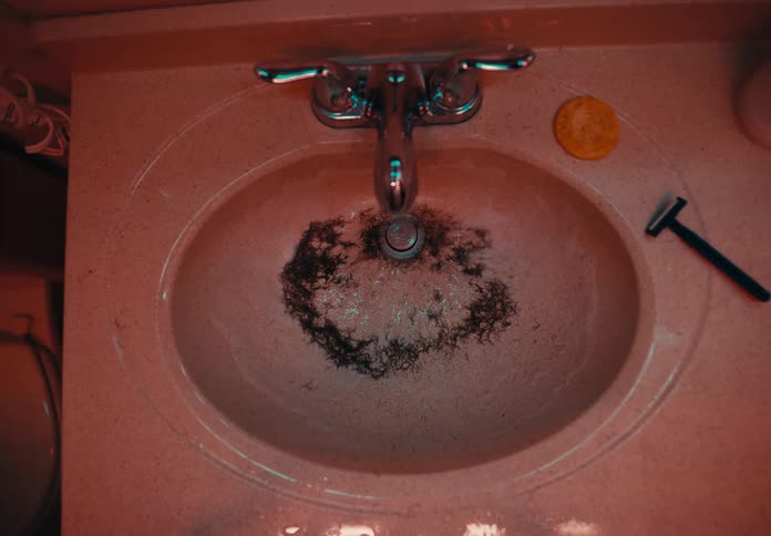 Water draining in bathroom sink leaving facial hair clippings behind