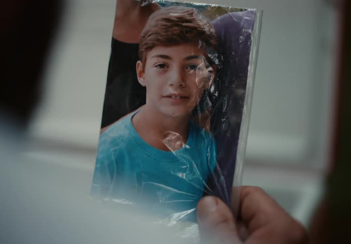 Person holding a photo wrapped in plastic of a young boy
