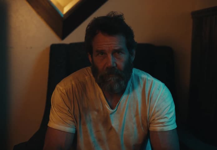 A man with a graying beard is sitting on a chair