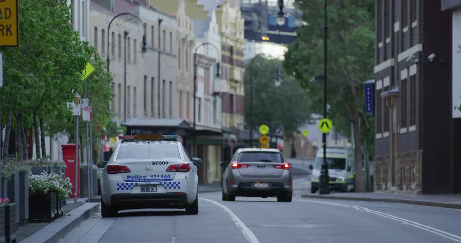 A vehicle drives down a tree lined street in a city neighborhood