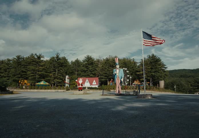 Man tapes a paper sign on a flagpole near a minigolf