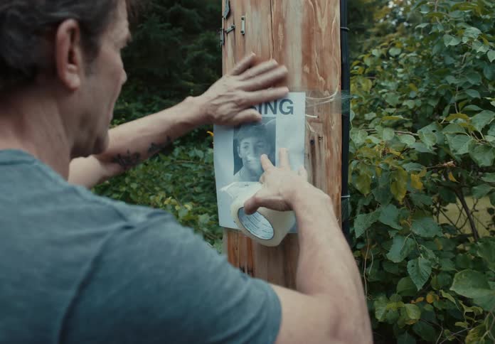 Man tapes a missing sign to a wooden utility pole