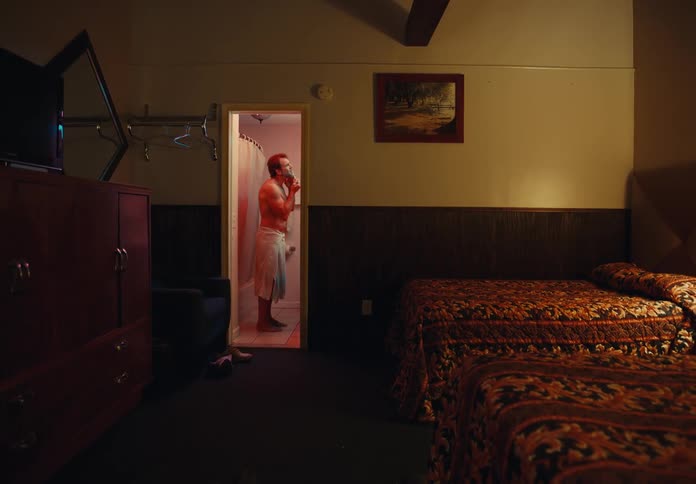 Man stands in hotel bathroom shaving