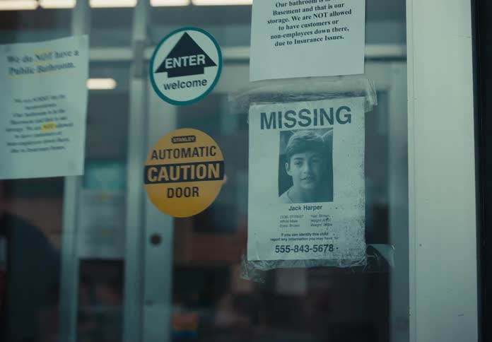 Automatic glass doors with missing child poster open for customers