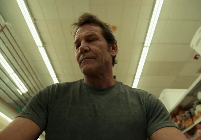 A man in a gray shirt is walking through a store shopping