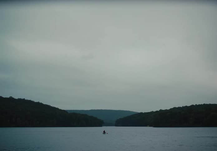 Man rowing in a kayak in a lake next to the mountains
