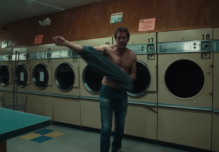 Man removing shirt from dryer at a laundromat then putting it on