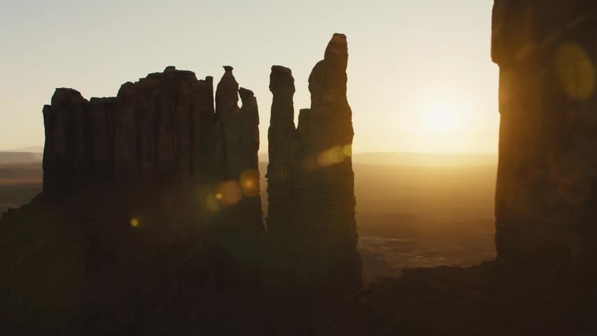 A desert with plateaus and cliffs with the sky and the sun in the background