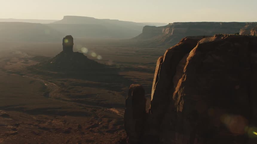 Mist obscures terrain on horizon as sun highlights mesa and plateaus