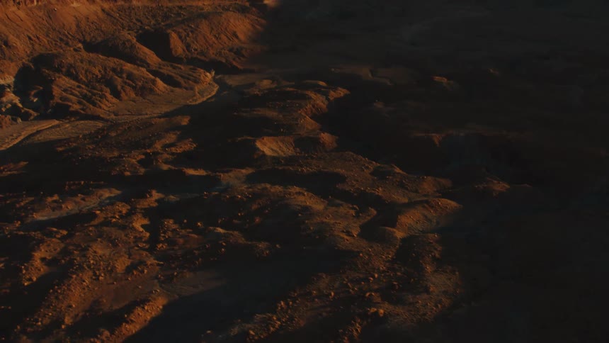 Ocean sits next to the rocky cliffs as mountains sit in the distance
