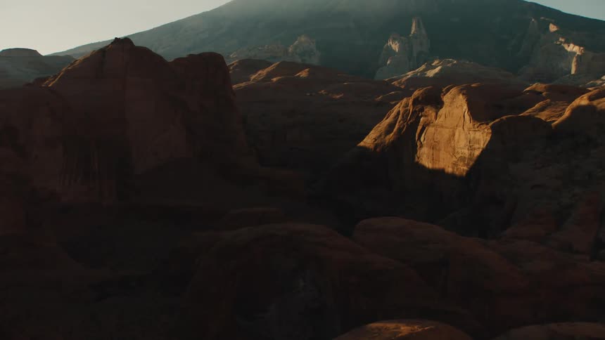 Aerial view of geological formations and mountains in the badlands desert at sunset