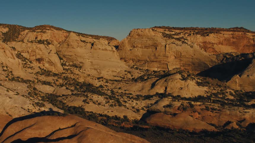 Vegetation dots canyons and valleys near plateaus under clear blue sky