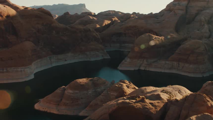 A calm blue lake lies in the valleys of a rocky area