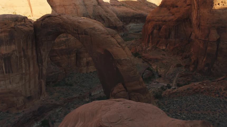 A rock formation in the shape of an arch hovers over a river in a canyon