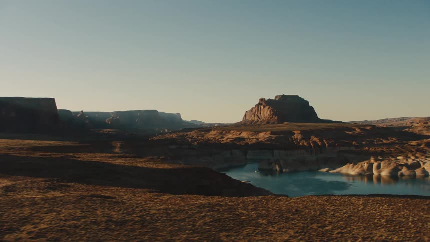 A deep blue river runs through a dry canyon in the desert