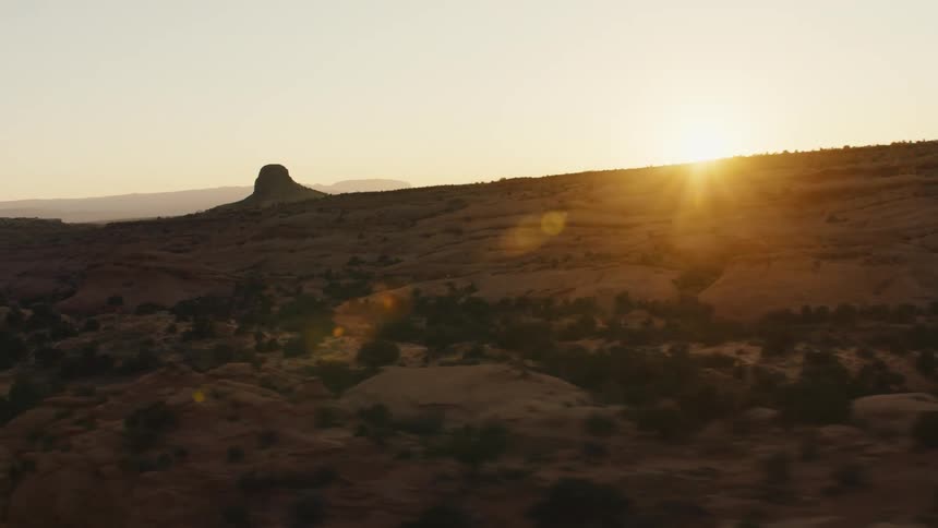 Sun hangs on horizon casting valley in badlands into shadow